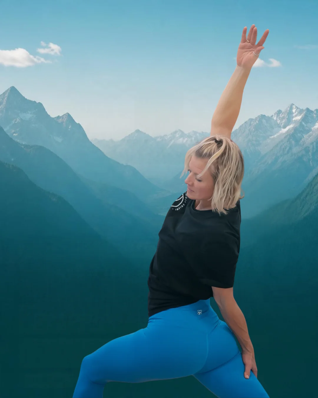 Yogalehrerin in gestreckter Pose vor einer Bergkulisse